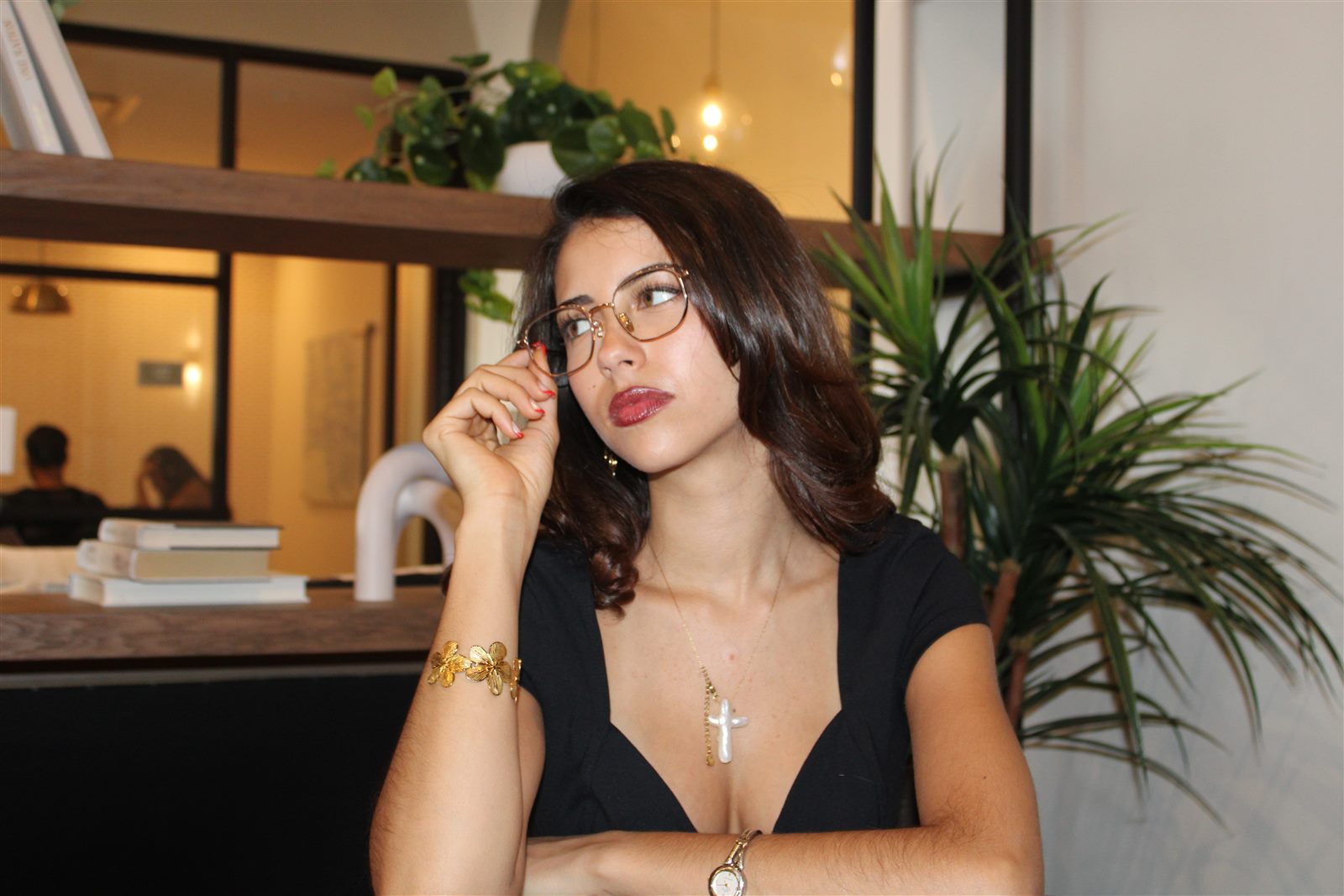 A woman adjusting her glasses in a café